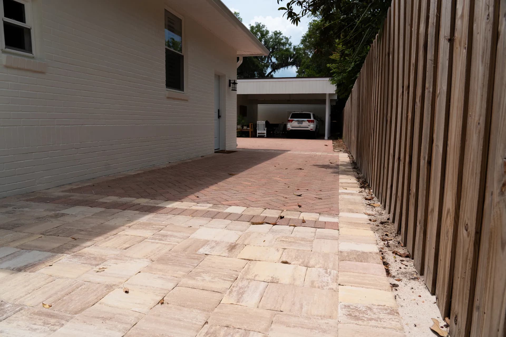 A finished two-tone paver driveway running alongside a home to the carport