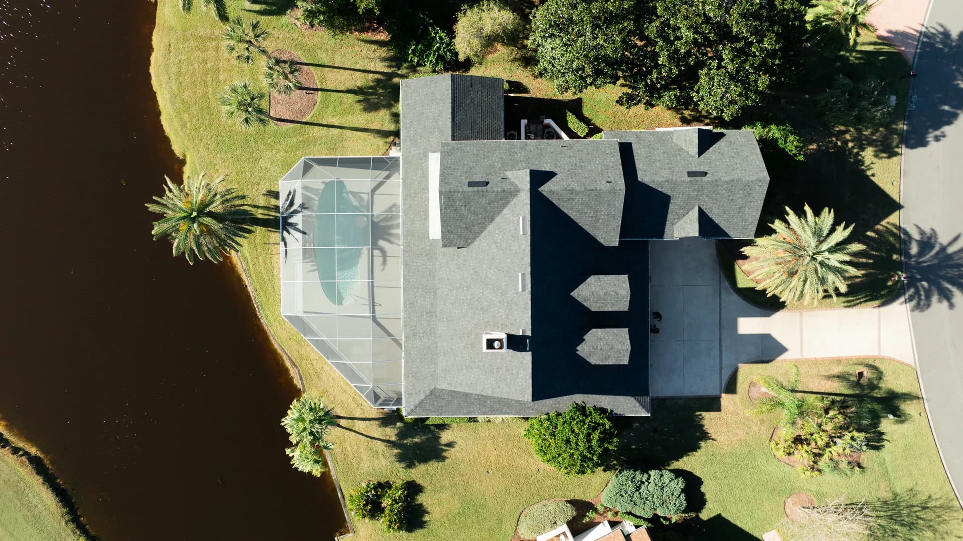 Aerial view of a lakefront home with a screened pool enclosure