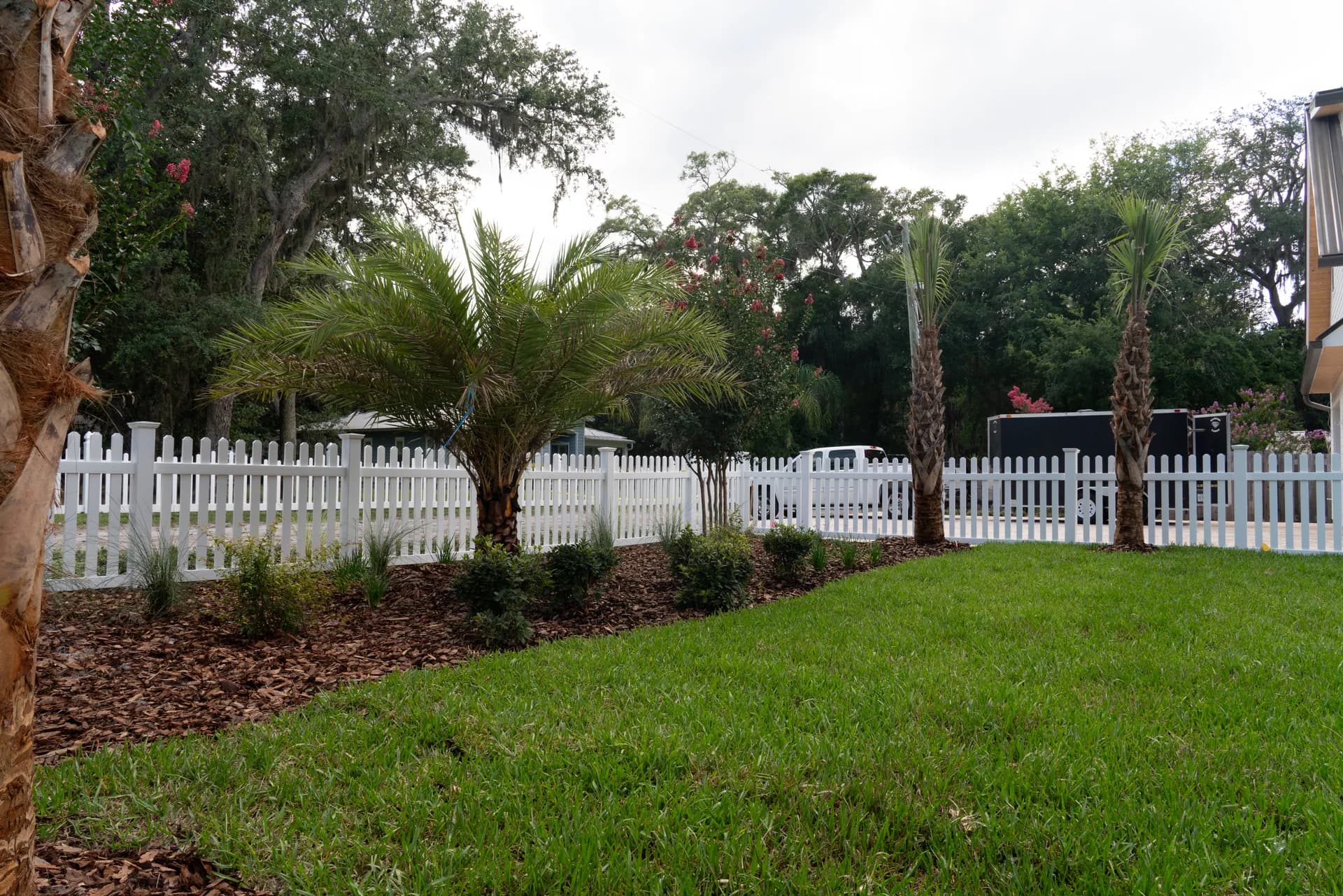 Established planting framing a paver court inside a picket fence