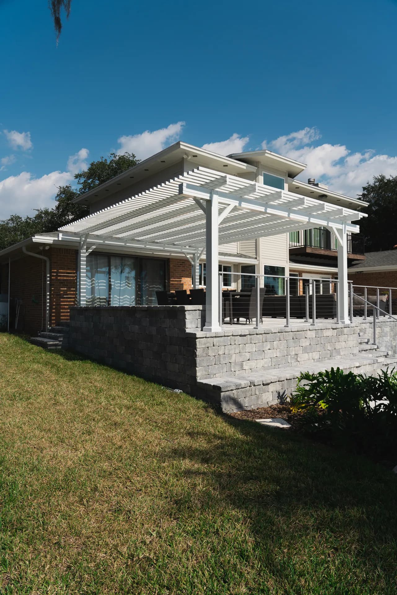 A white pergola over a newly finished raised paver deck