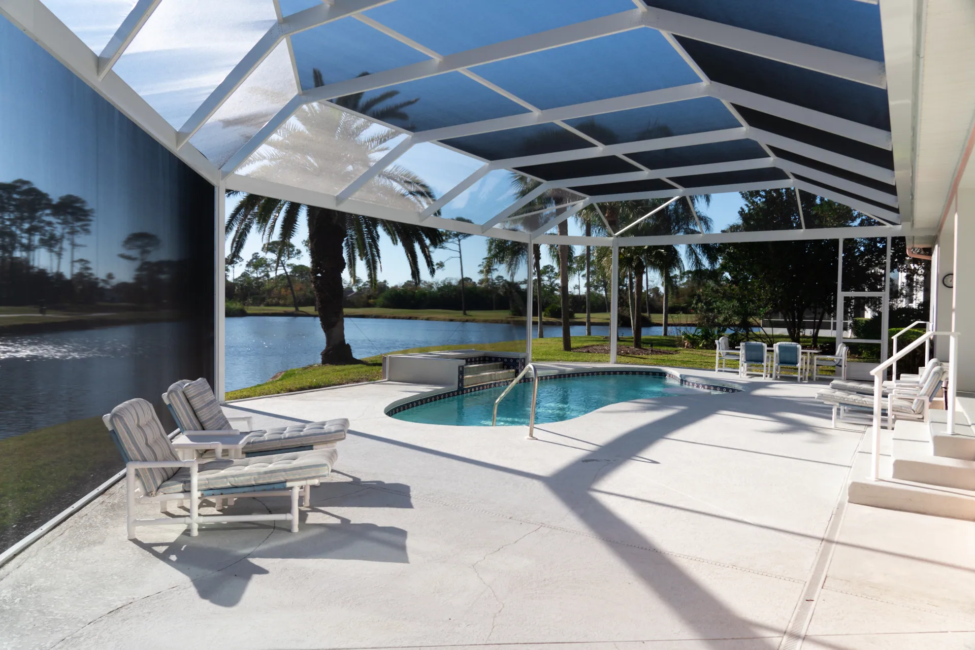 A pool deck set with loungers looking out over a lake