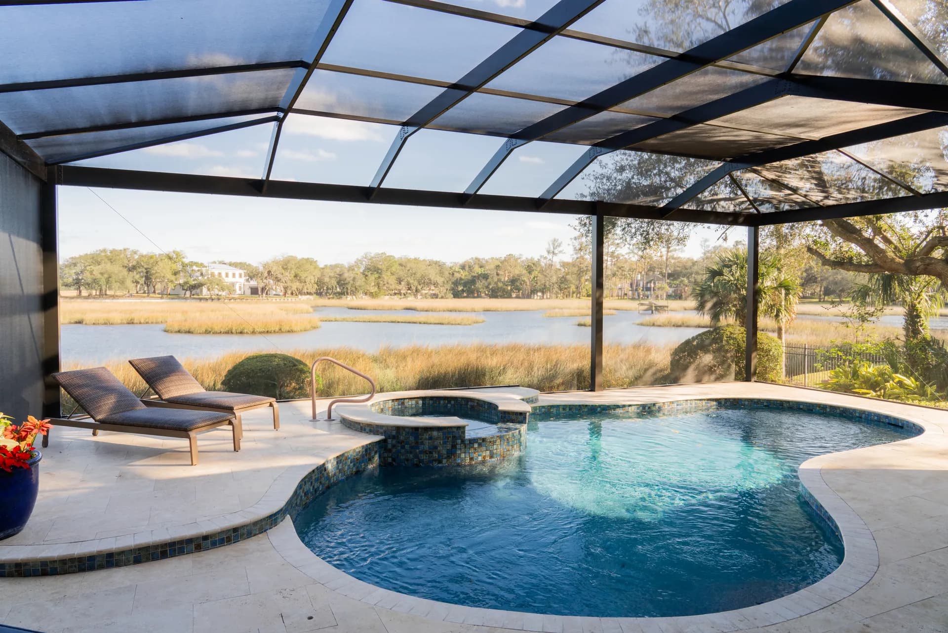 A pool and spa in golden evening light with an open marsh view beyond