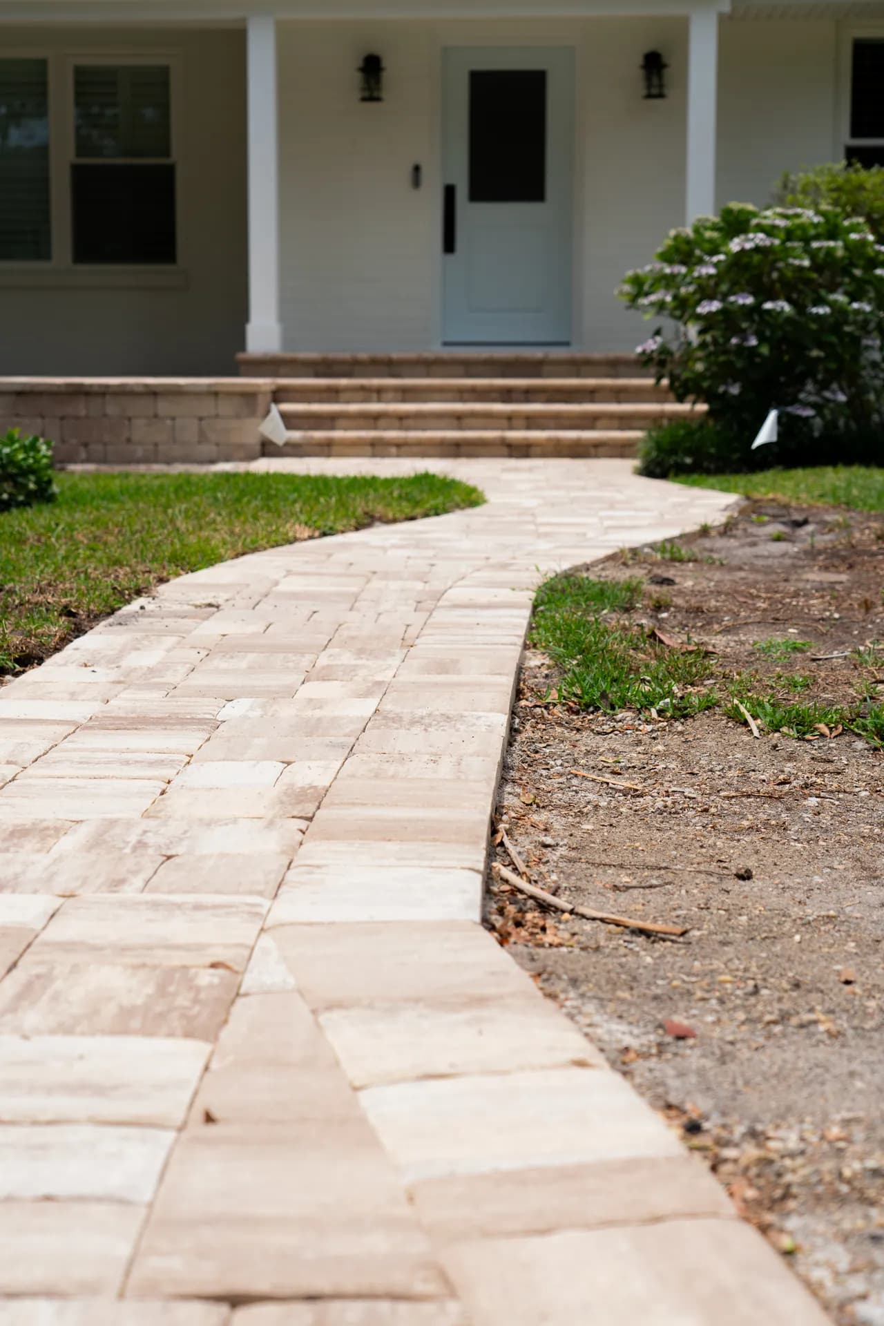 A curving paver walkway leading to a front entry with matching paver steps